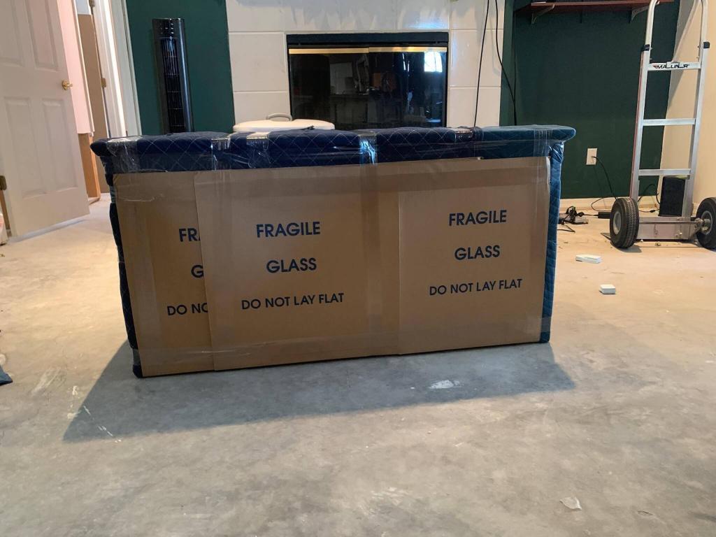 The same dresser fully wrapped in moving pads and tape on a protective mat