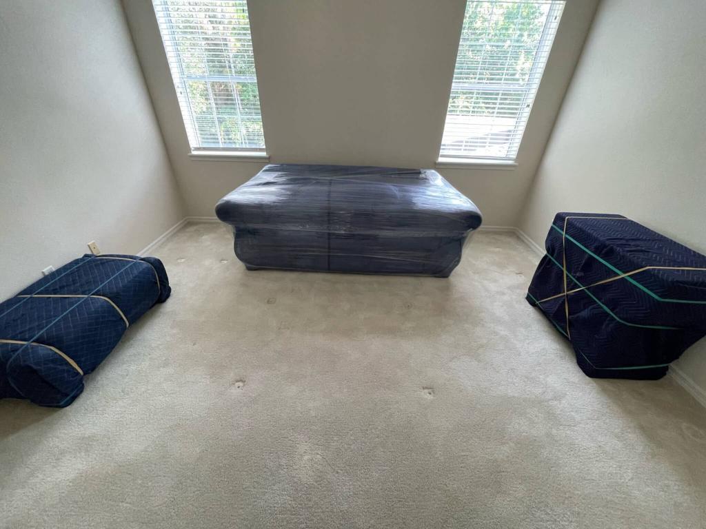 Living room furniture wrapped in blue and black moving pads by Black Swan Moving before loading