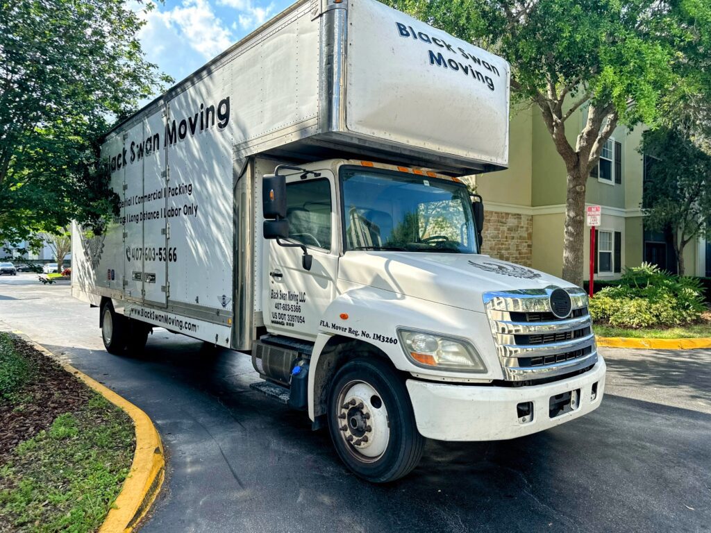 Black Swan Moving truck parked beside a residential building