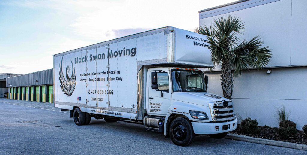 Black Swan Moving box truck parked beside palm trees, ready for a New Smyrna Beach, Florida move