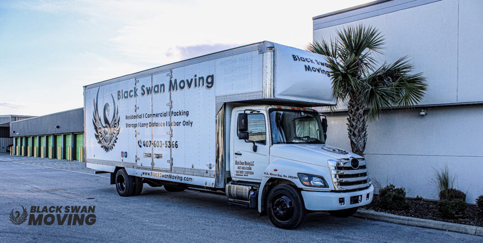 Black Swan Moving box truck parked beside a storage building