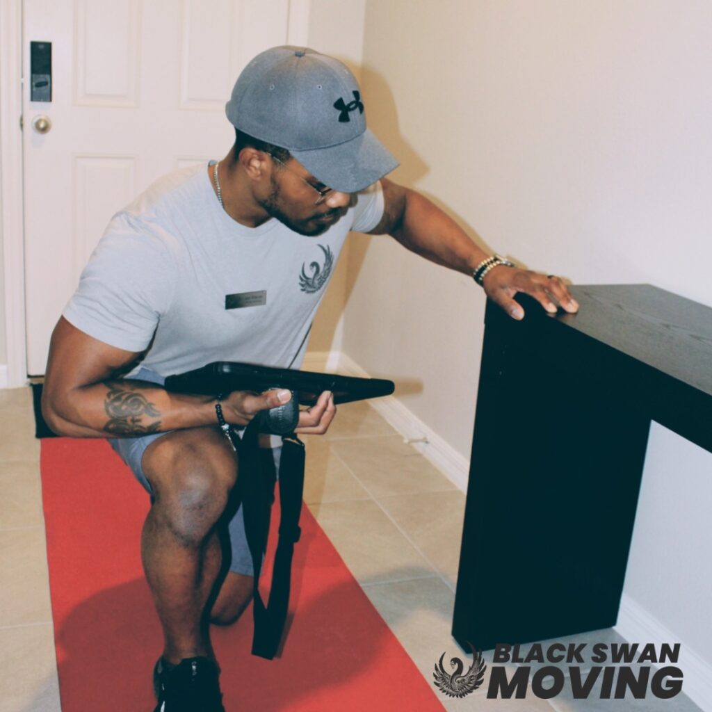 Black Swan Moving crew handling a large mirror over a red floor runner