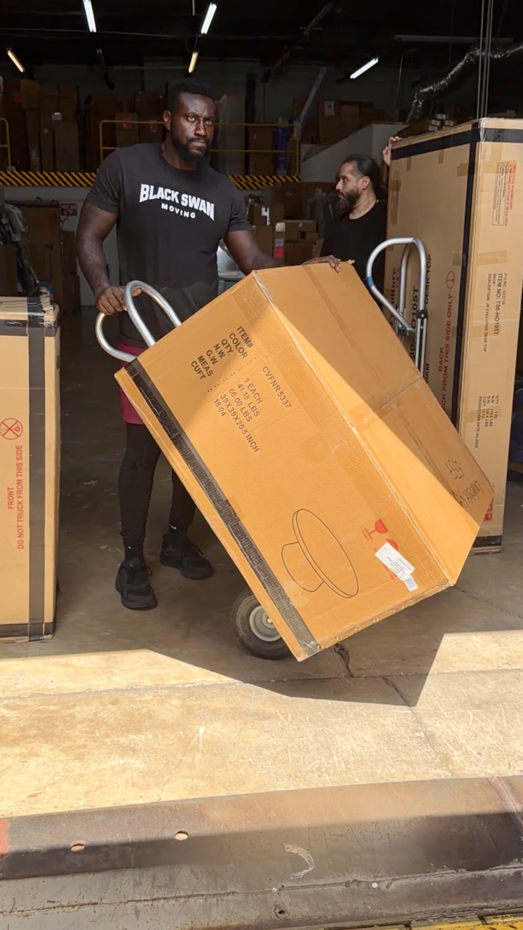 Black Swan Moving crew transporting boxed commercial furniture with moving equipment