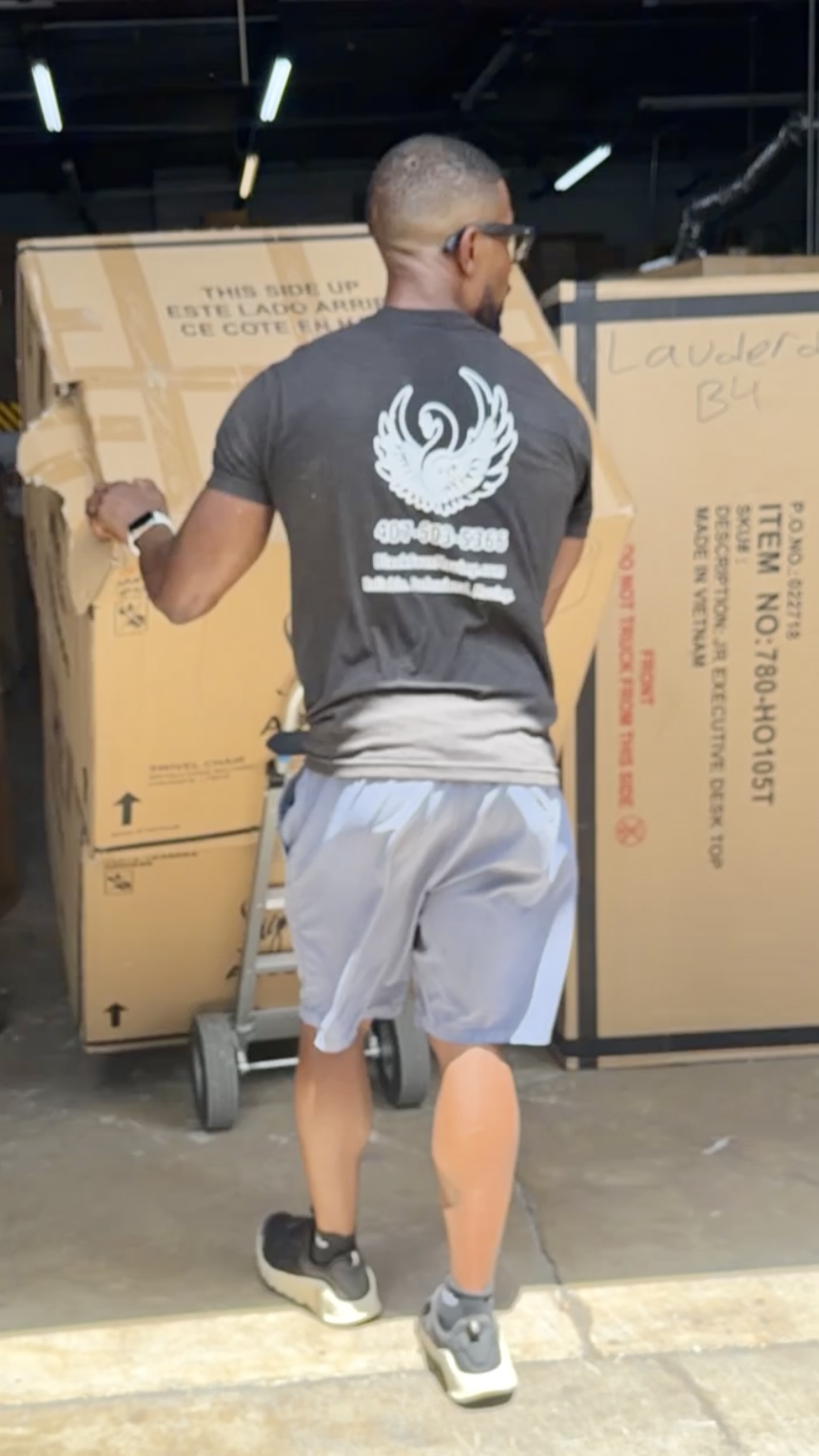 Black Swan Moving professional transporting a large boxed item in a warehouse