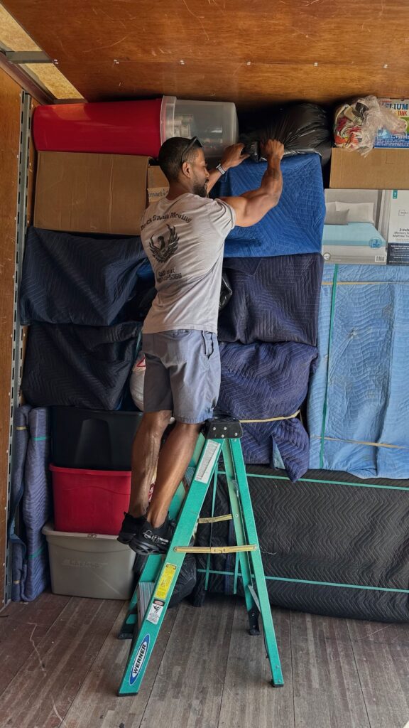 Black Swan Moving mover on a ladder stacking items inside a moving truck