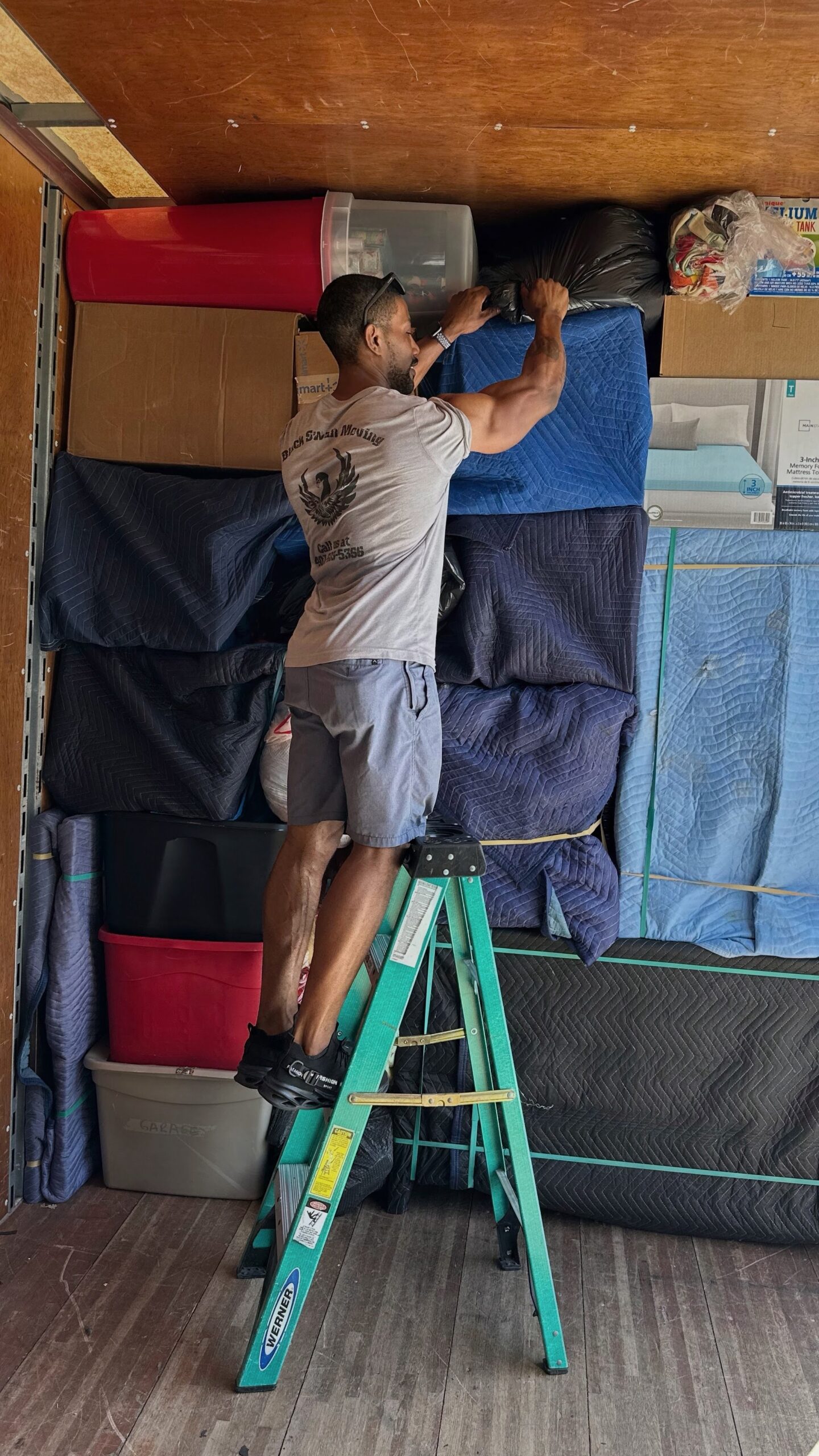 Black Swan Moving professional securing protected furniture inside a moving truck