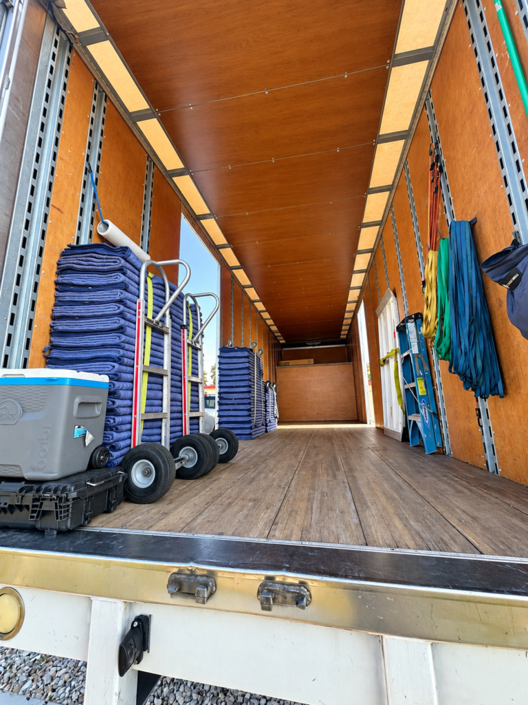 Inside a Black Swan Moving truck stocked with moving blankets, dollies, straps, and a ladder