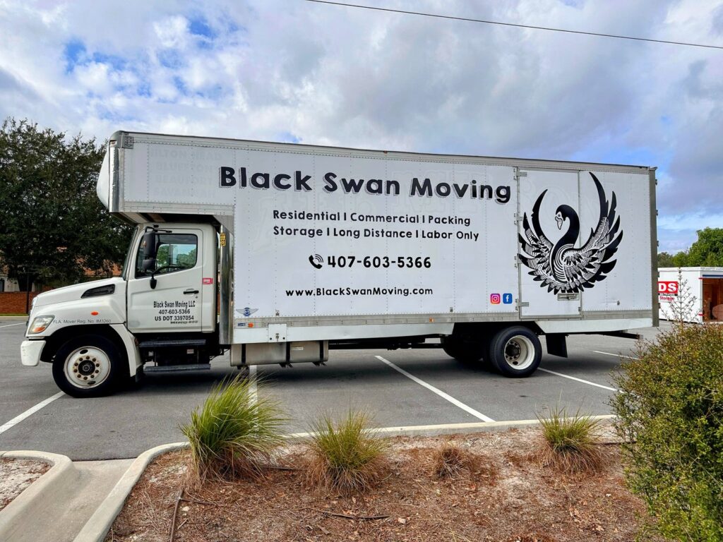 Black Swan Moving box truck, side view showing the swan logo and services