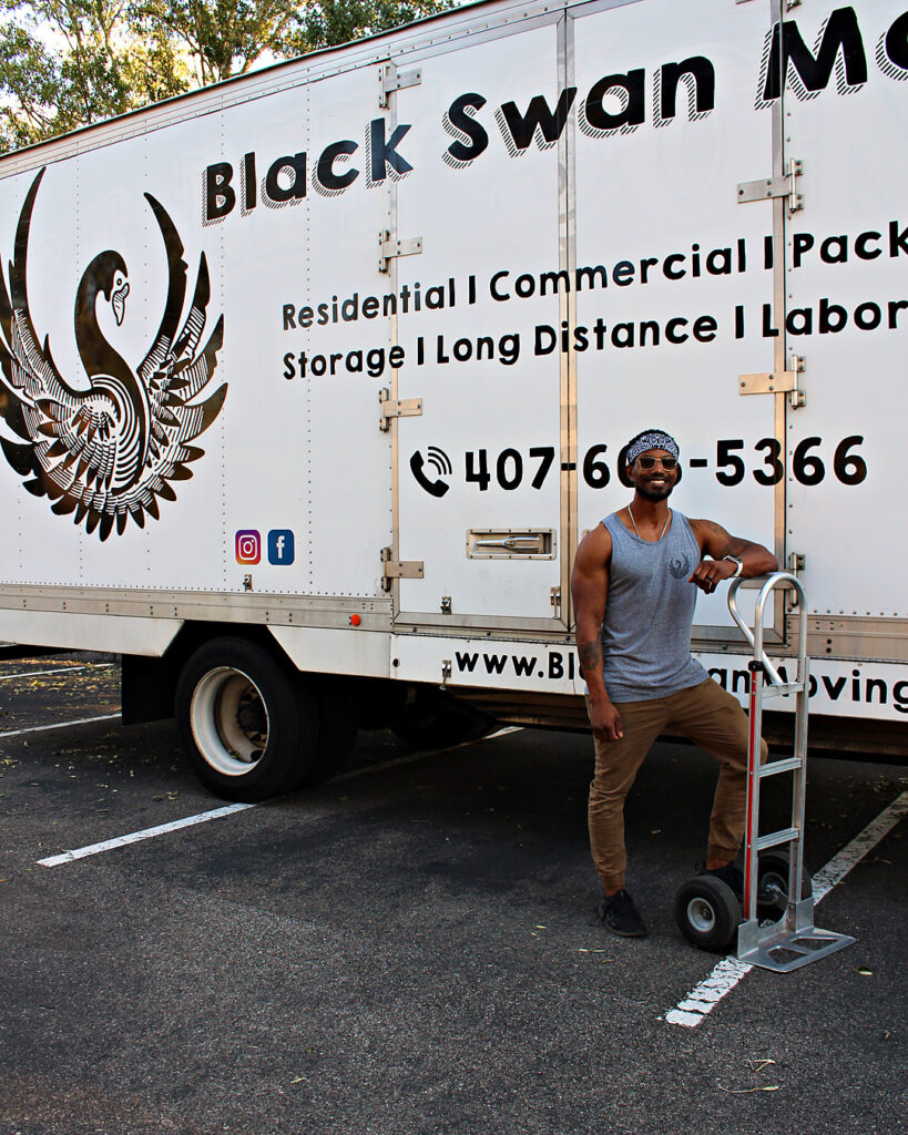 Winter Garden Movers - Black Swan Moving | 5-Star Movers in Central Florida Black Swan Moving crew member with a hand truck in front of the Black Swan Moving box truck
