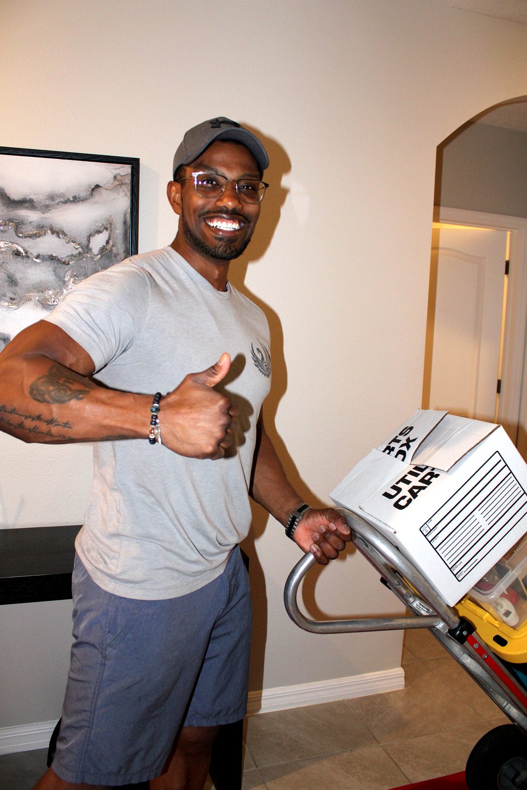 Smiling Black Swan Moving crew member giving a thumbs up beside a hand truck