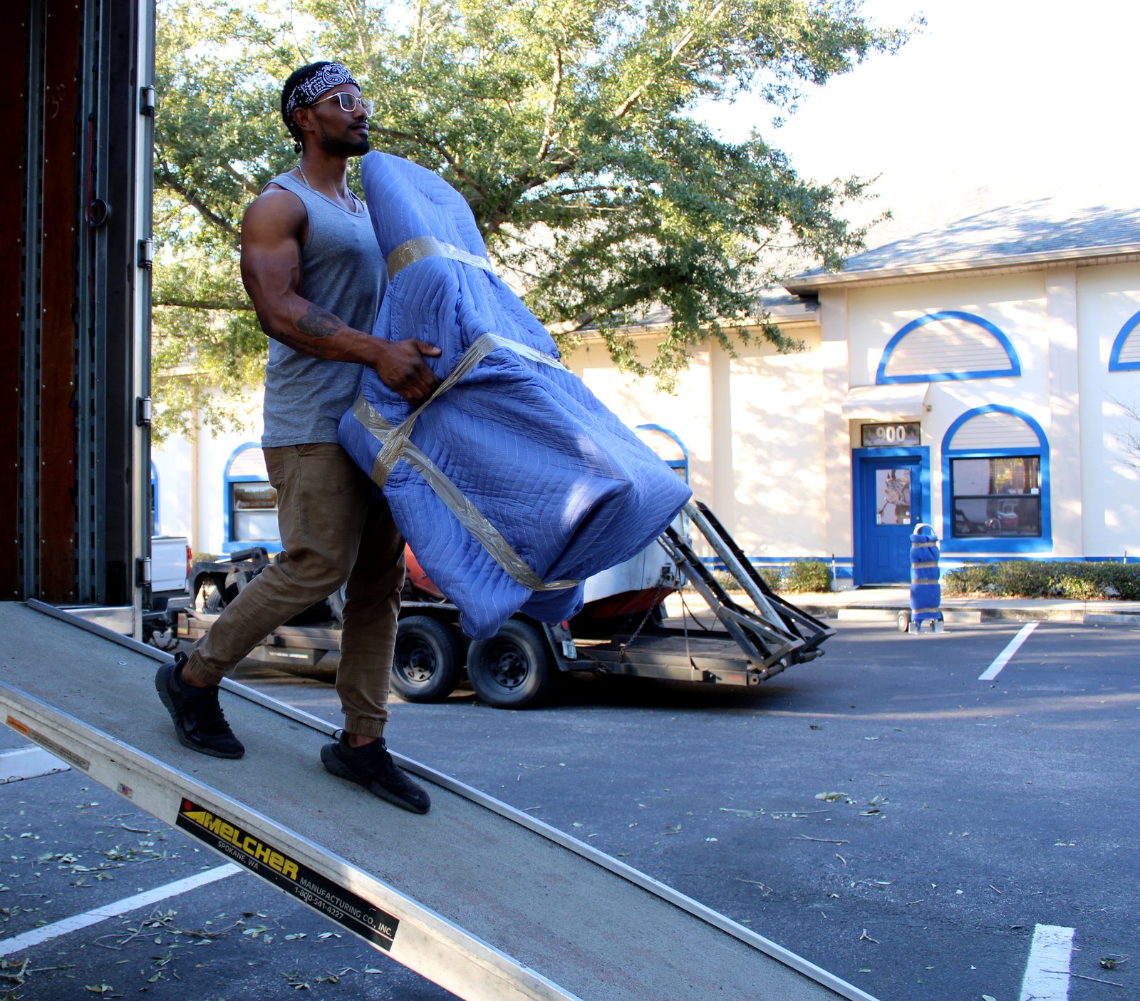 Black Swan Moving mover carrying a blanket-wrapped item down the truck ramp