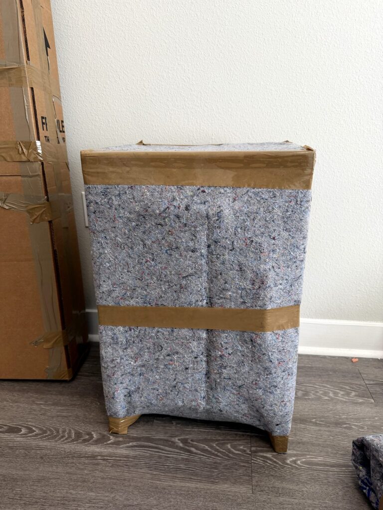 The same nightstand wrapped in a gray moving pad and taped