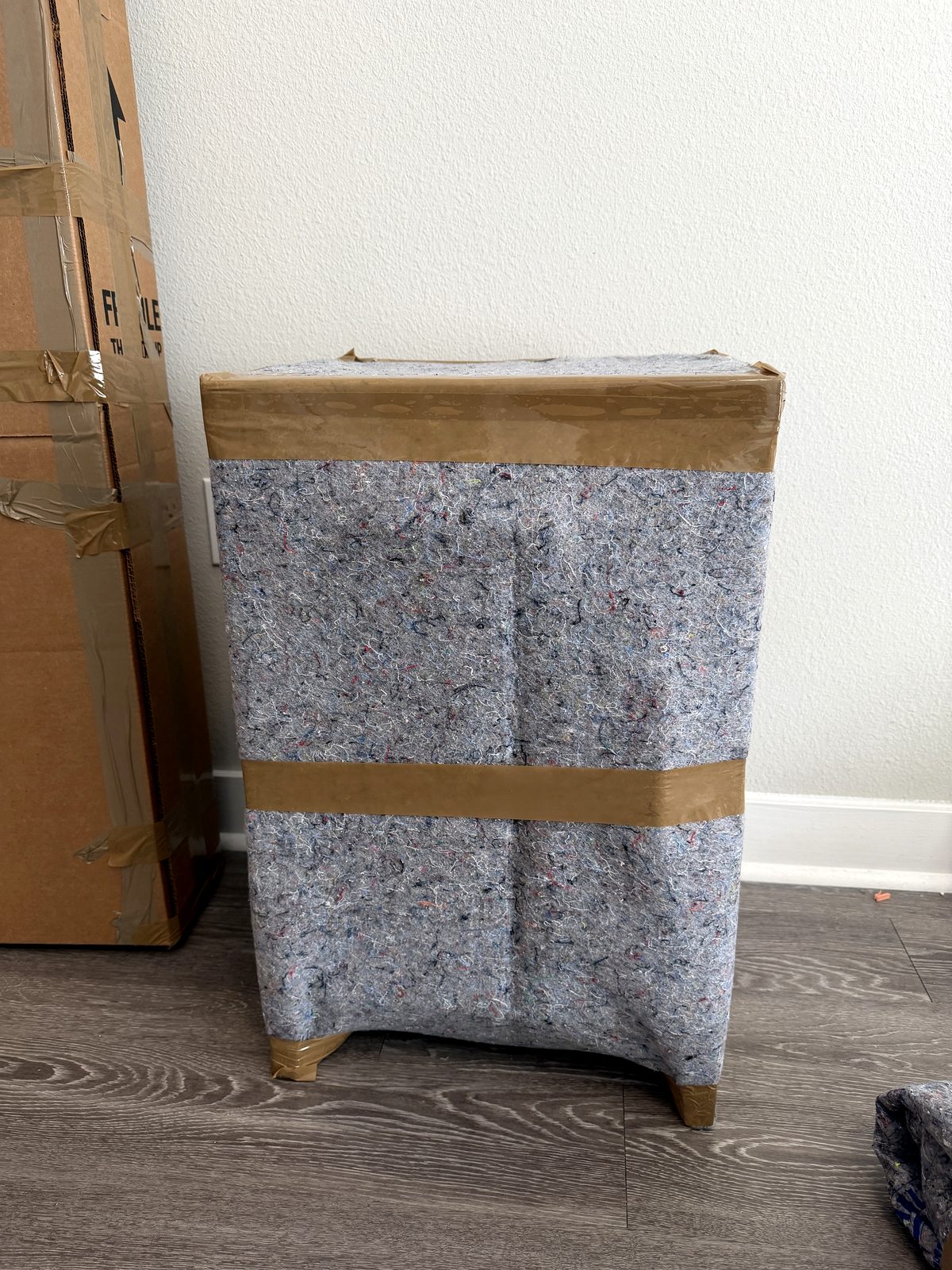 Nightstand wrapped in a moving pad and taped for the move