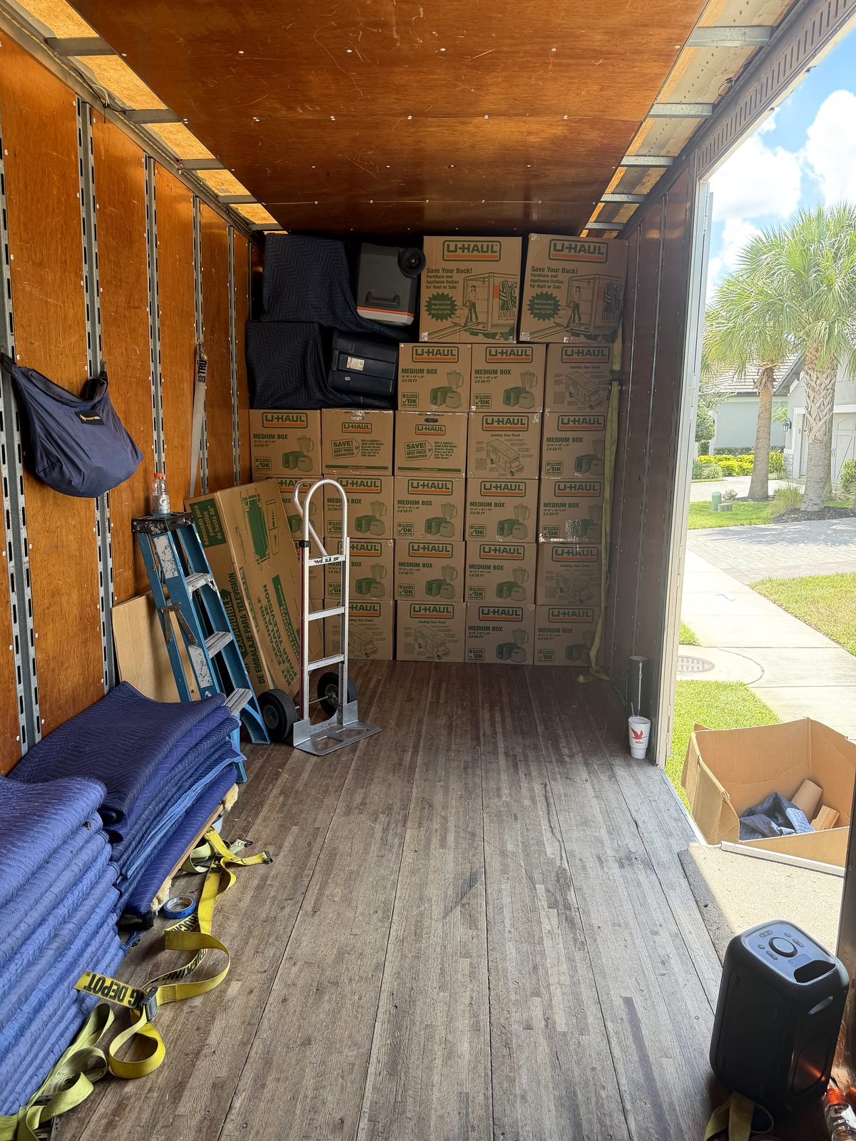 Black Swan Moving truck interior with stacked boxes, moving pads, straps and a dolly