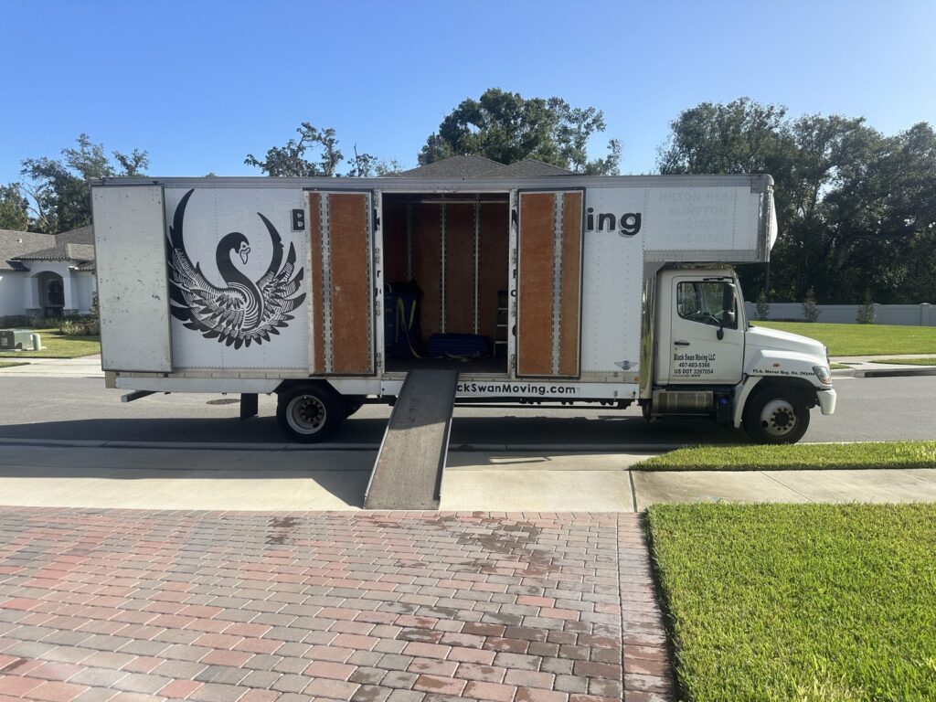 Black Swan Moving box truck with its ramp down in front of a Central Florida home