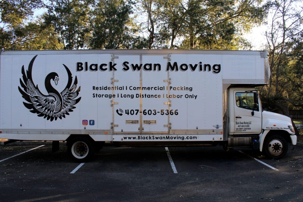 Tavares Movers - Black Swan Moving | 5-Star Movers in Central Florida White Black Swan Moving box truck parked in a lot, with the swan logo, list of services, and phone number on its side