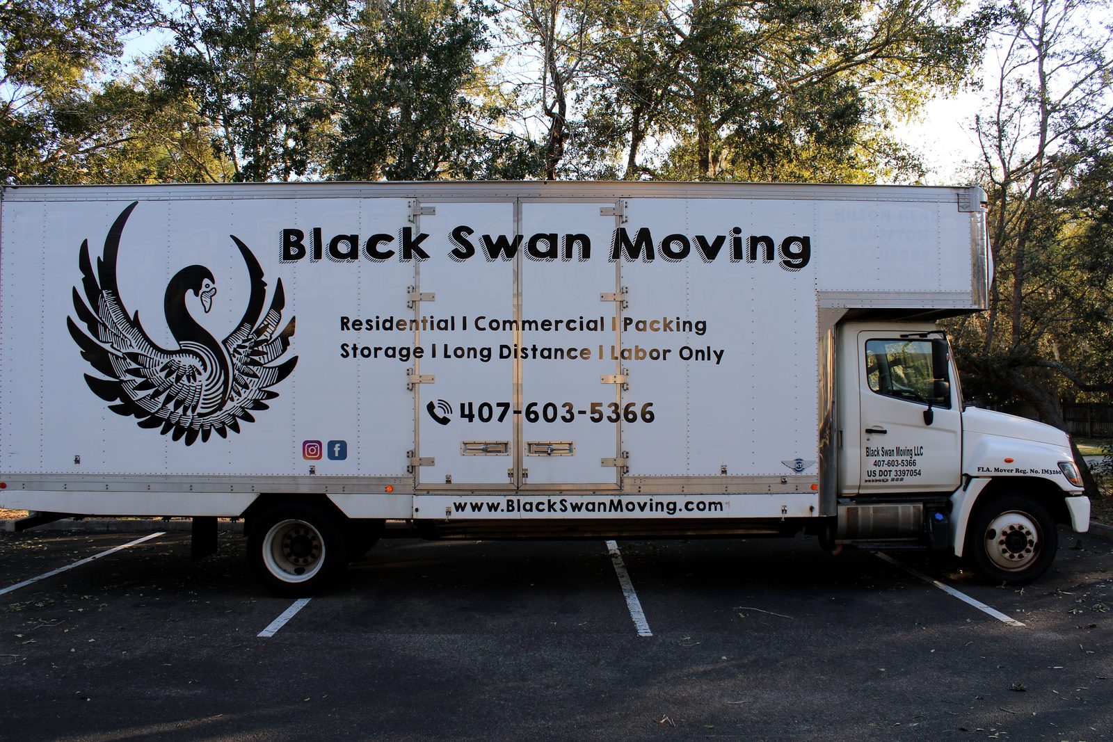 Full side view of the Black Swan Moving box truck with logo, services and phone number