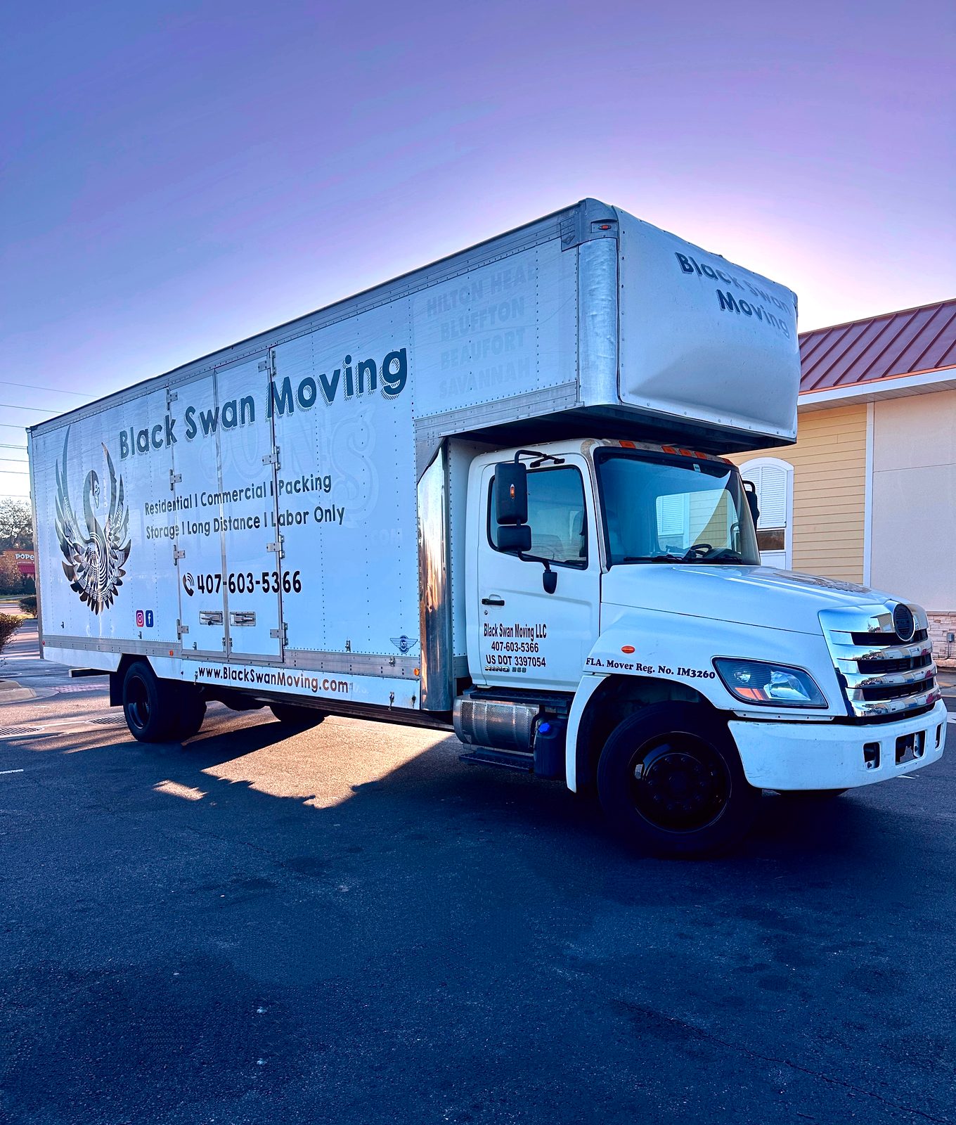 Black Swan Moving box truck parked at sunset under a purple sky