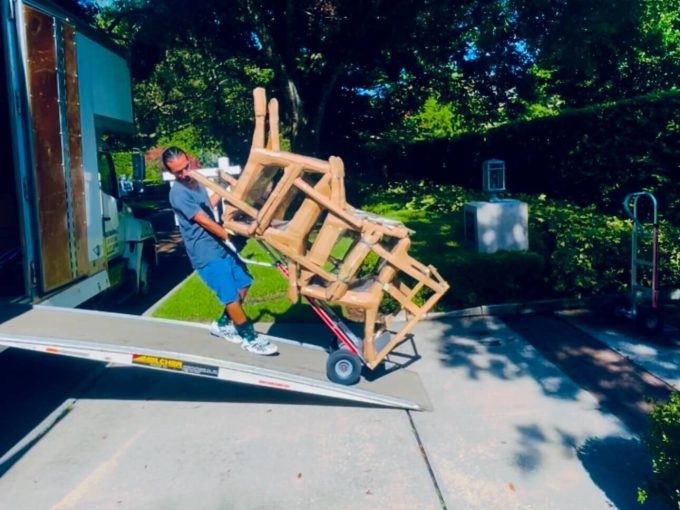 Mover with dolly loading patio chairs onto the Black Swan Moving truck.